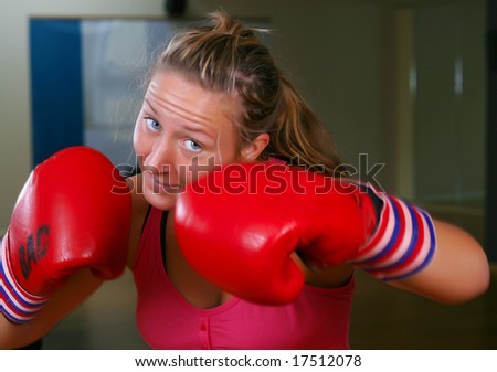 Sporty girl in boxing gloves punching (action shot)