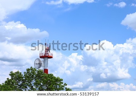 Air traffic control communications tower against cloudy blue sky, symbolic background
