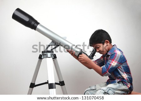 A boy looks through a telescope