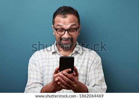 Middle aged man of Indian origin looking at his mobile phone with a surprise Foto stock © 