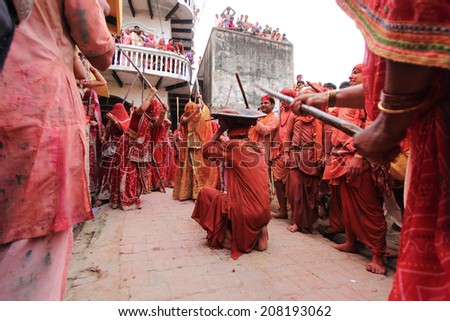 NANDGAON - MAR 22: Women beat up men with long sticks as a ritual in the Lathmar Holi celebration on March 22, 2013 in Nandgaon, India. Holi is the most celebrated religious festival in India.