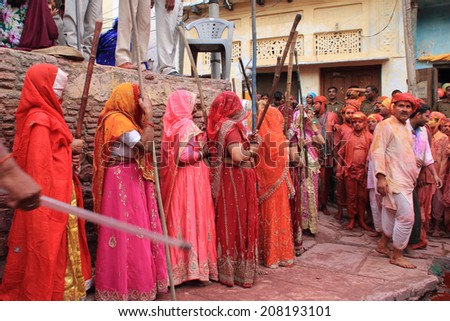NANDGAON - MAR 22: Women carry  long sticks to beat men as a ritual in the Lathmar Holi celebration on March 22, 2013 in Nandgaon, India. Holi is the most celebrated religious festival in India.