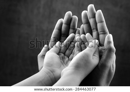 Monochrome image of  hands of a kid covered by hands of as elder. Ideal for concepts of care and protection