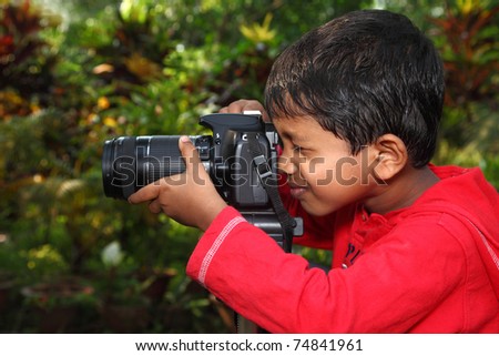 A boy focusing with a camera fixed on tripod