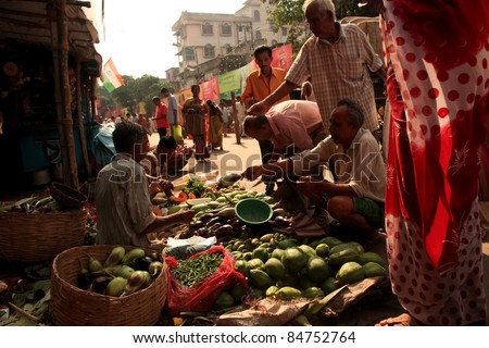 KOLKATA - OCTOBER 17: Customers buy vegetables from a street vendor in a busy road on October 17, 2010 in Kolkata, India. Its a common practice in India to sell vegetables in open markets and streets.