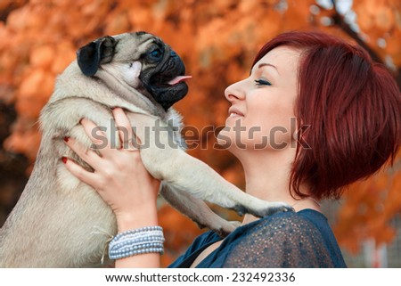 Girl smiling at her pug pet dog