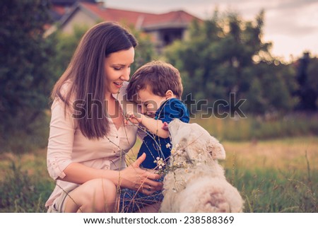 Son being licked by a dog while in mothers arms