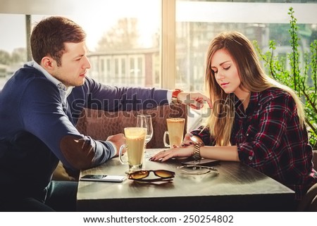 Girl is looking at watch while he is touching her hair