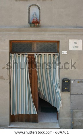 Blue/white curtain in a doorway, blowing with the wind, keeping the sun out of the house