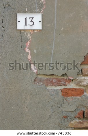 Number 13 on an old wall. Signifies bad luck. A crack runs from the sign to a bad part of the wall.