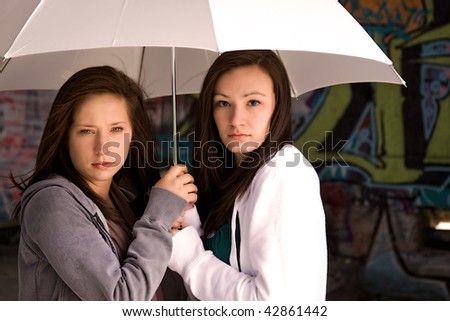 Two Teenage Girls Under an Umbrella as a Protection