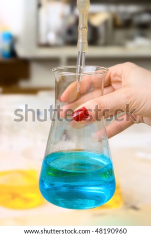 beautiful woman\'s hands holding a flask with reagent in chemical laboratories