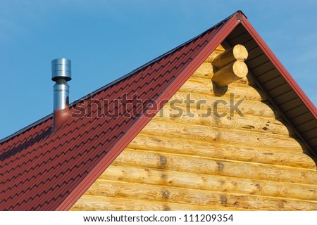 Top of country wooden house with red roof and metal smokestack
