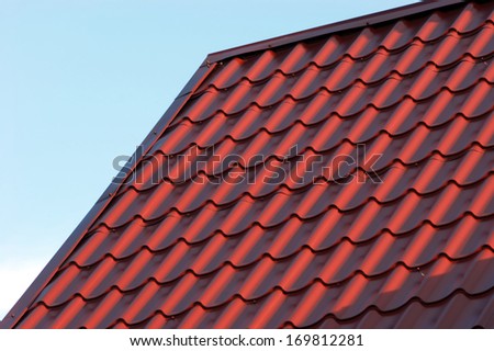 Part of red house roof from metal tile over blue closeup