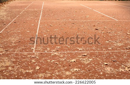 End of summer sport season. Empty tennis court with lot of yellow leaves in autumn
