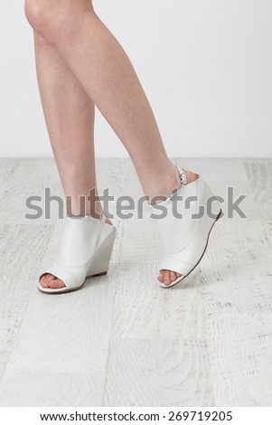 Woman feet in summer shoes on the white wooden floor