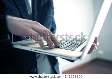 Male Businessman Working While Standing on the Laptop in Office Area. Computers Technology Photo Collection.