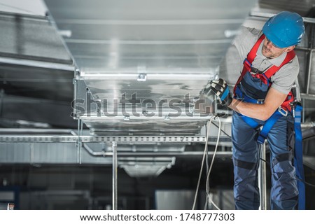 Industrial Theme. Warehouse Heating and Cooling System Installation by Professional Caucasian Technician. Commercial Building Ventilation Rectangle Canals. Air Distribution. Photo stock © 