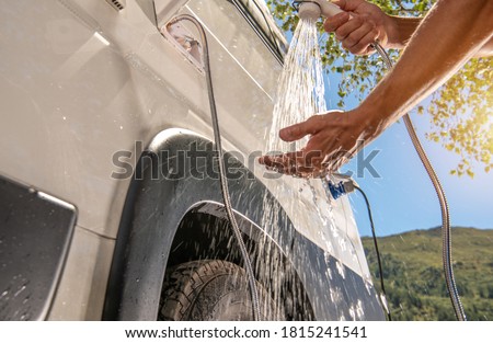 RV Camper Van Outdoor Shower Taking. Caucasian Men Preparing For Shower While on Wilderness Boondocking Camping. Recreational Vehicle Motorhome Outside Water Outlet.