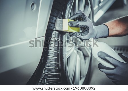 Caucasian Car Detailing Worker Taking Care of Modern Vehicle Tires and Alloy Wheels. Vehicle Detail Cleaning. Automotive Industry Theme. Stock fotó © 
