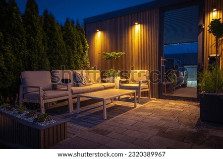 Lounge and Dining Area at Modern Residential Backyard Decorated with Outdoor Lights, Plants, Garden Table and Chairs. Cozy Summer Evening. Foto d'archivio © 
