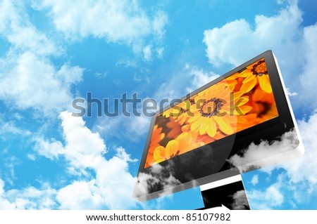 Technology and Nature Theme. Modern Computer Display Between the Clouds. Cloudy Blue Sky. Orange Flowers on the Screen.