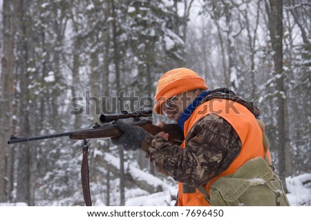 Senior hunter aiming a deer in his sight under the snow,Quebec, Canada