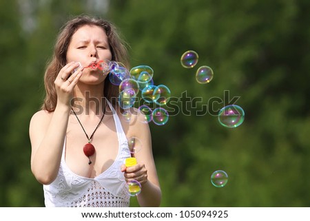 Beautiful young woman blowing soap bubbles outdoors