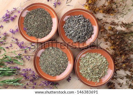 Medicinal herbs in clay saucers on wooden table
