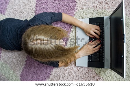 Girl lying on the floor and using her laptop. Top view