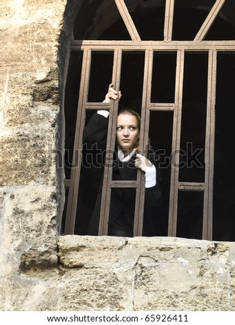 Teen girl looks out of the fortress jail window