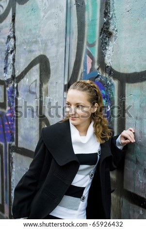 Cute teen girl stays near the wall with graffiti