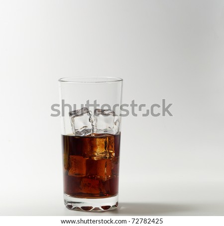 Glass of cola with ice cube on white