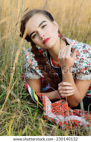 Young peasant woman, dressed in Hungarian national costume, posing over nature background