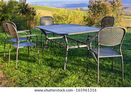 Picnic table and chairs on the lawn in courtyard of country house at morning time