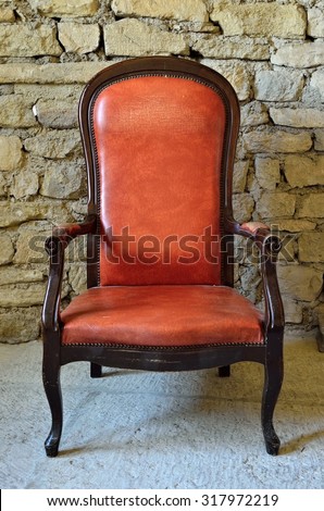 LE BARROUX, FRANCE - JUL 17, 2014: The old leather armchair on a background of a stone wall in the castle of Le Barroux. Le Barroux castle very popular tourist attraction in Provence, France