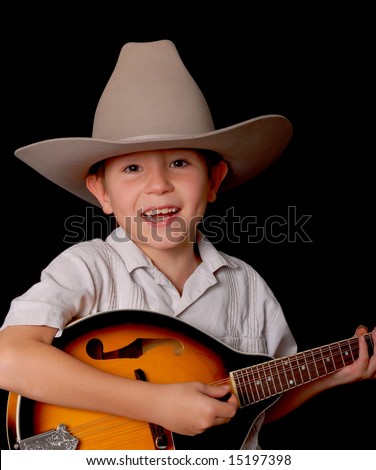 Young boy wearing a cowboy hat isolated on black playing the mandolin