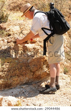 Senior geologist tap a rock formation with a hammer
