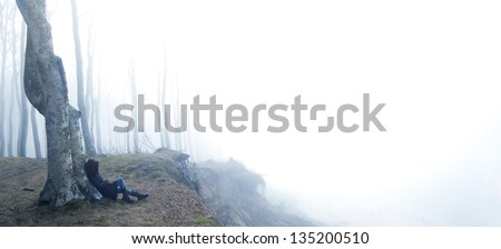 Emotions conceptual image. Sad and lonely person sitting in dark forest.