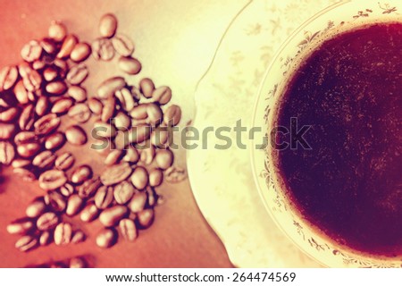 Coffee beans and cup of hot coffee. Vintage instagram picture. Antique porcelain cup.