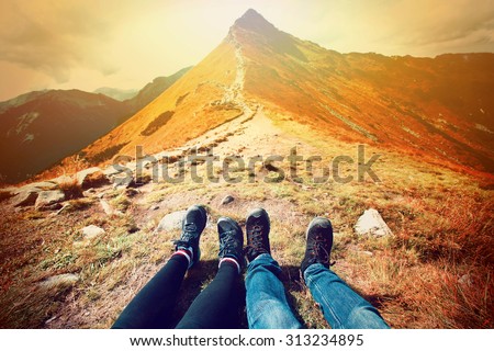 Tourism in mountains. A couple of tourists rest on the mountain path. Nature in mountains at autumn.