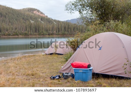 Camp of two tents pitched up on shore of Yukon River in remote wilderness of Yukon Territory, Canada