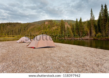 Two tents pitched on a sand bar alongside McQuesten River, Yukon Territory, Canada, in remote boreal forest wilderness