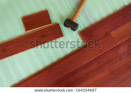 Home improvement construction laying stained brown wooden bamboo hardwood boards flooring and rubber mallet tool