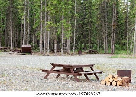 Campground on gravelled area inforest with camping table and fire-pit for each campsite