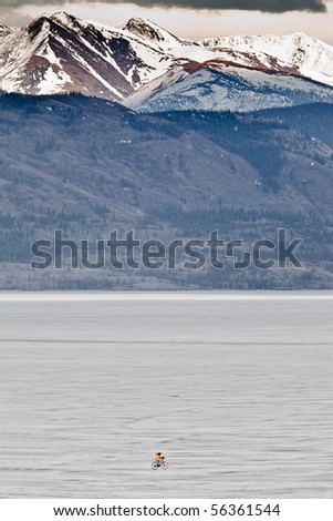Person riding a bike on vast frozen lake