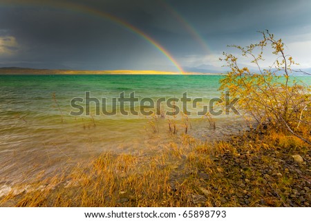 A Thundershower producing a rainbow over the gree-blue waters of pristine Lake Laberge, Yukon Territory, Canada.