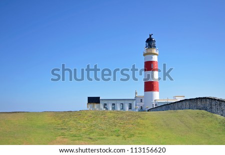 Point of Ayre Lighthouse with green lawn in the foreground and clear blue sky in the background. Location Isle of Man