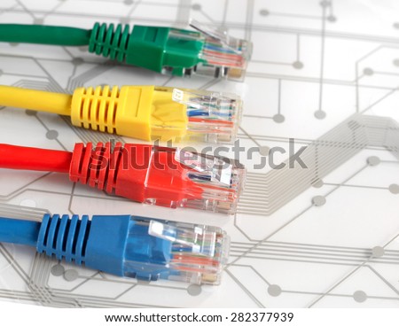 Four Multi Colored Network Cables. Red, Yellow, Green, Blue Color. Cables are lying on top of White Circuit Board