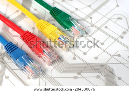 Four Multi Colored Network Cables. Red, Yellow, Green, Blue Color. Cables are lying across on top of White Circuit Board